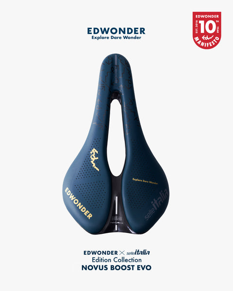 A dark blue bicycle saddle with gold branding and text, centered on a light gray background. The image includes the text 'EDWONDER Explore Dare Wonder' at the top, a red circular 'EDWONDER 10 YEARS MANIFESTO' badge at the top right, and 'EDWONDER x seaItalia Edition Collection NOVUS BOOST EVO' at the bottom.